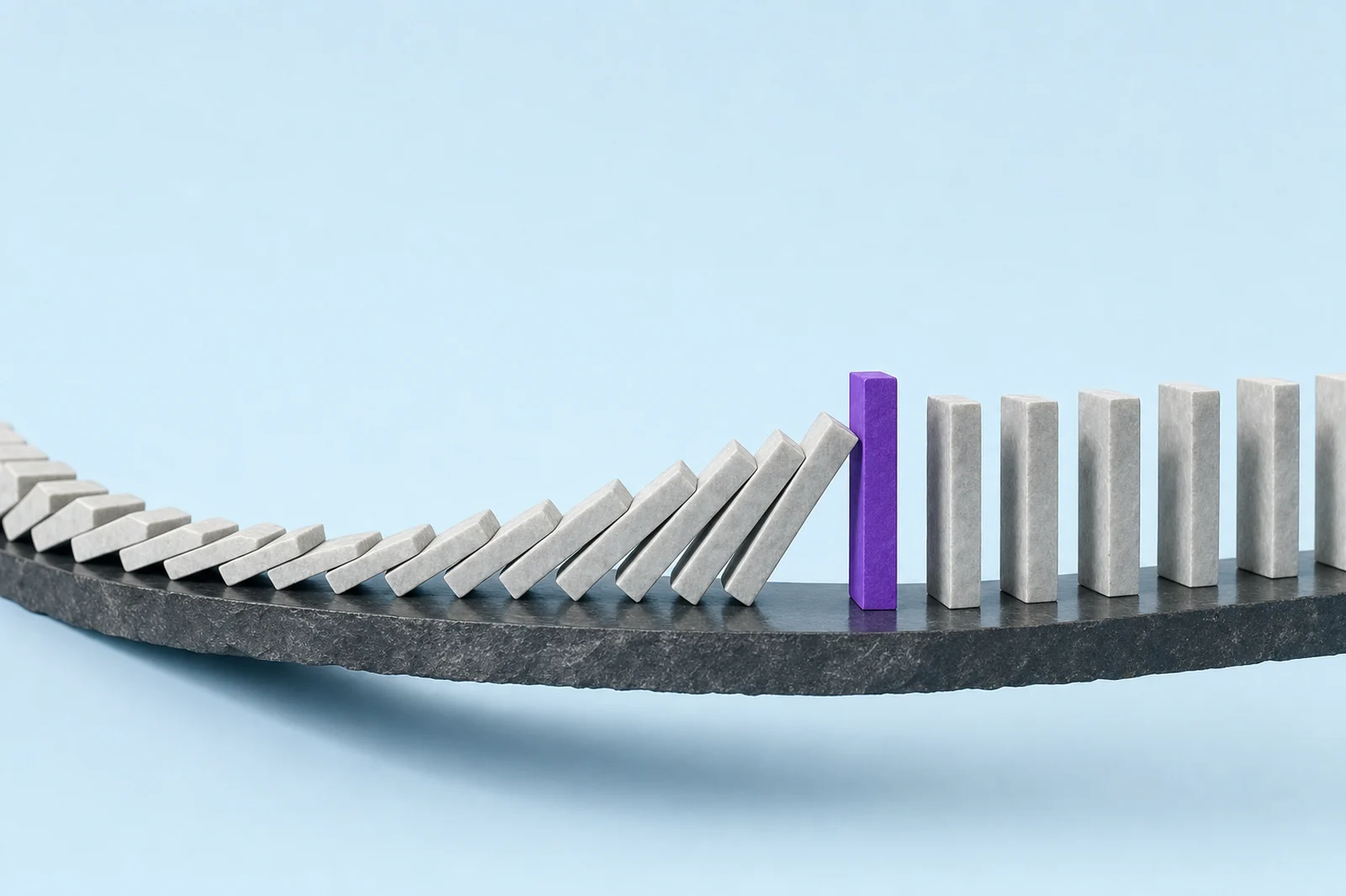 A run of stone dominoes mid-fall on a slate ledge, stopped by one upright glowing violet block